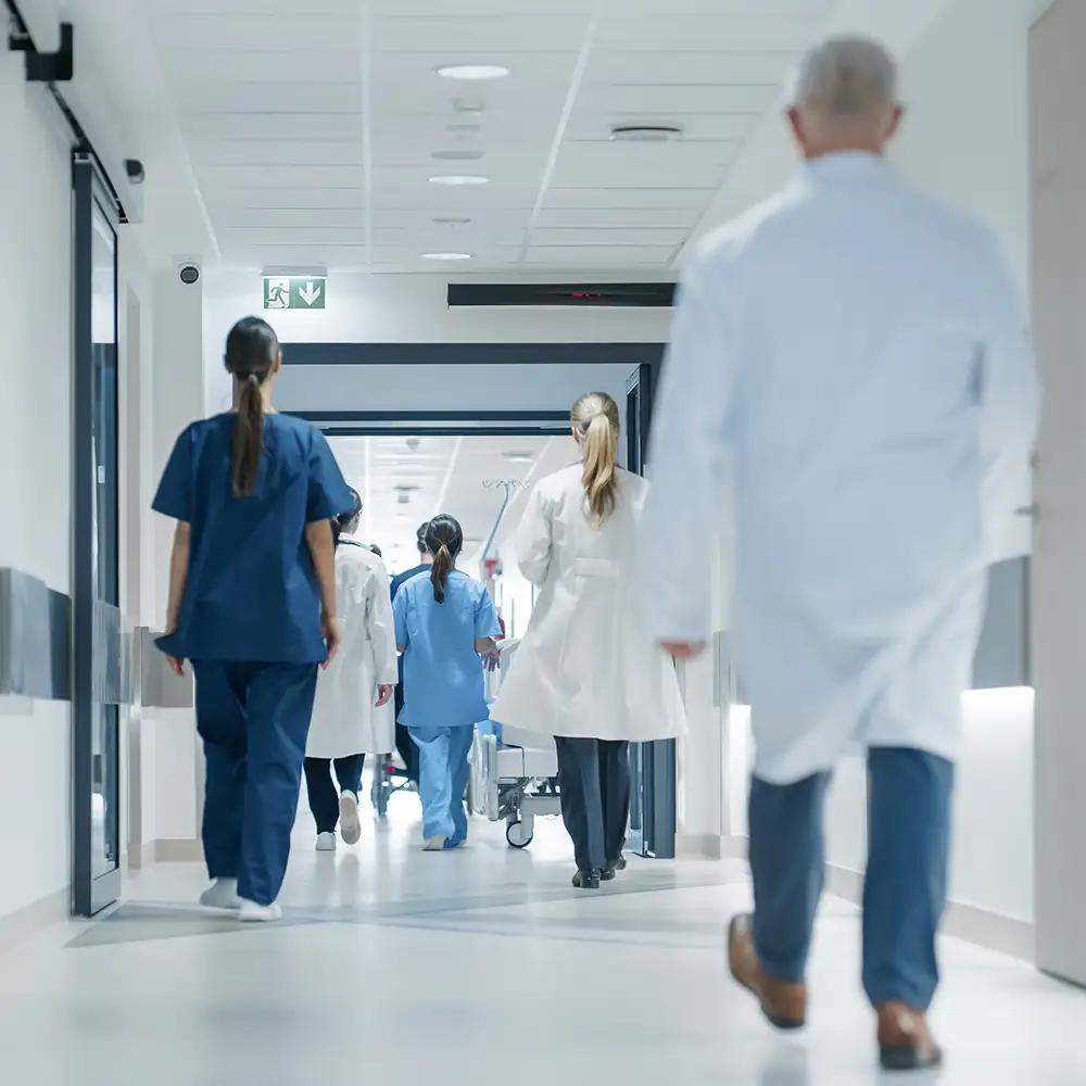 View of physicians from behind walking down hospital hallway