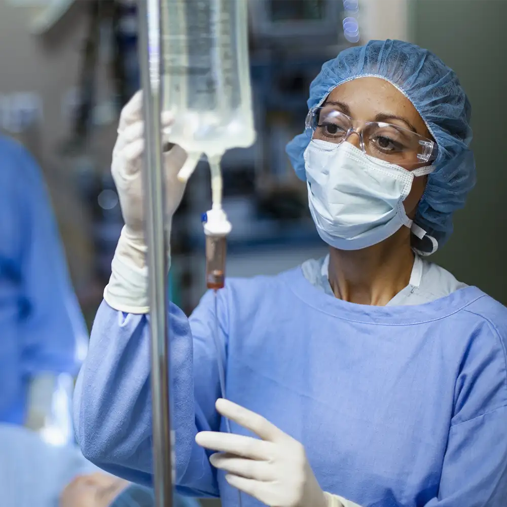 An anesthesiologist with a mask on monitoring the IV bag during a surgery