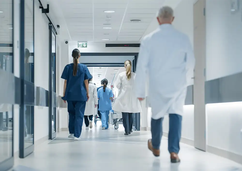 View of physicians from behind walking down hospital hallway