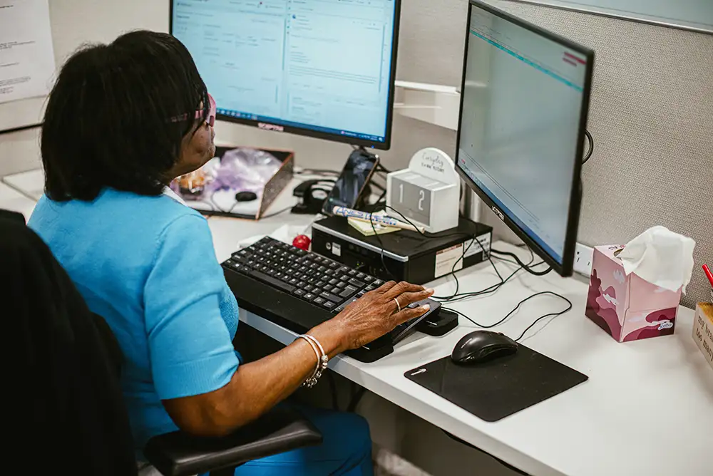 Back view of woman sitting at desk infront of two screens