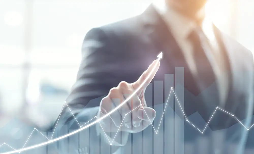 A man in a business suit pointing up with a bar graph overlay on top of the image