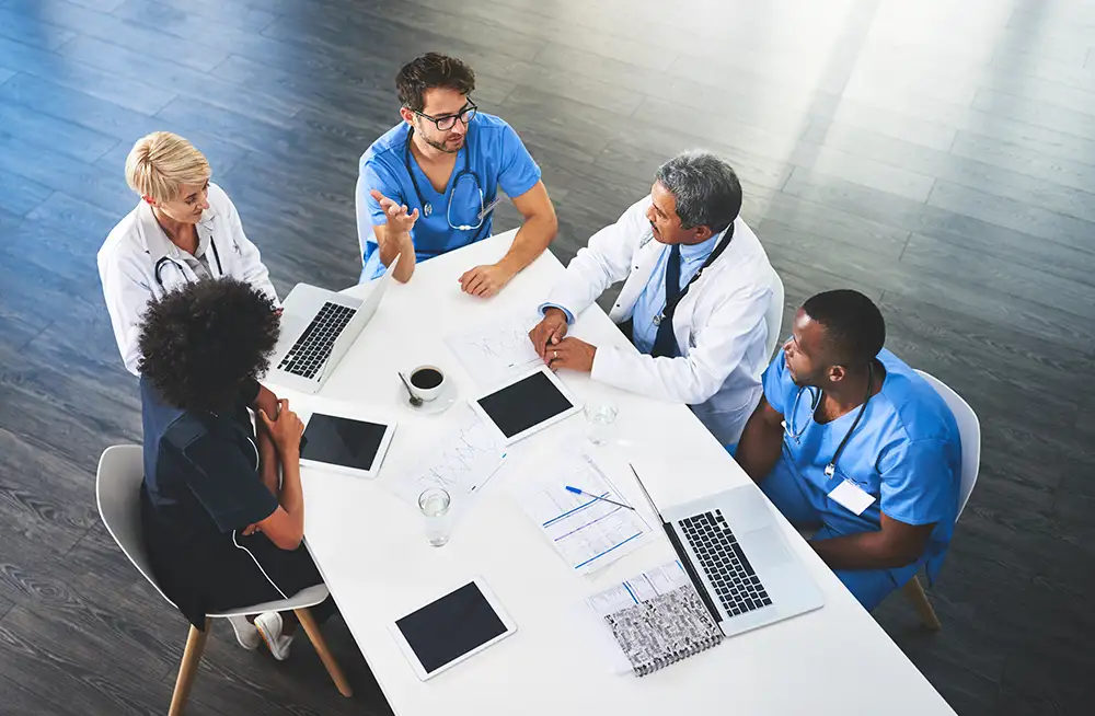 Physicians and business people sitting at table with paperwork
