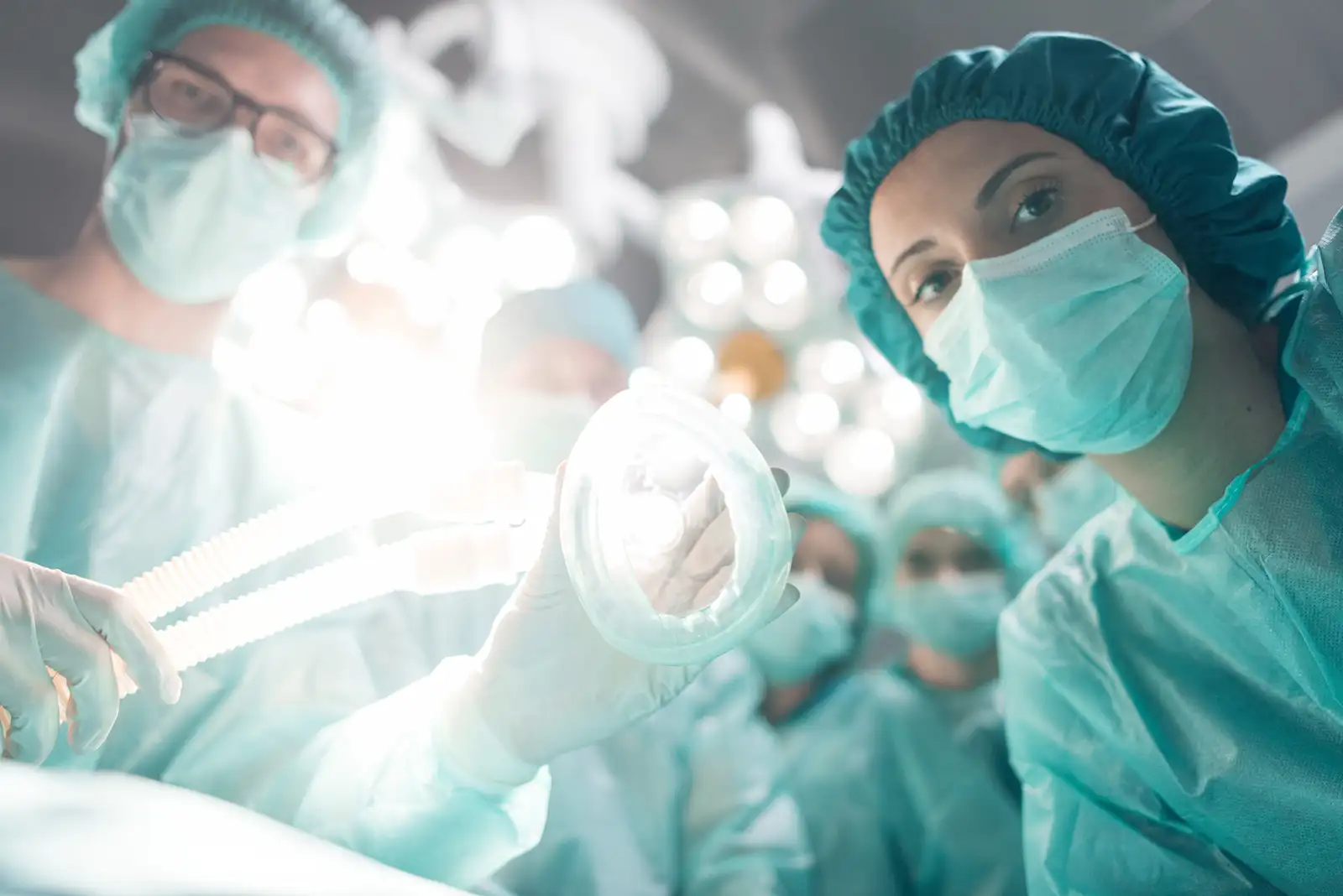 A group of physicians looking down at a patient ready to administer anesthesia