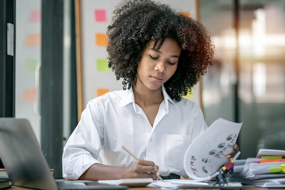 A woman sitting at a desk flipping through pages of charts