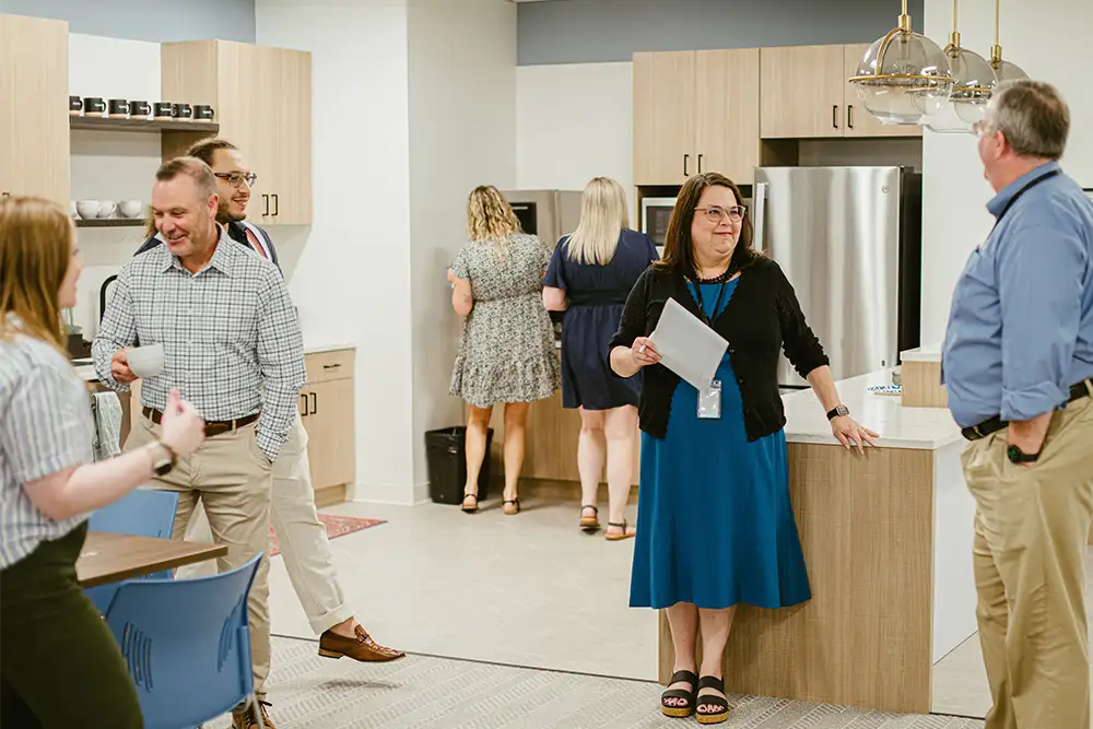A group of people from the Anesthesia Resources team talking in groups around their office