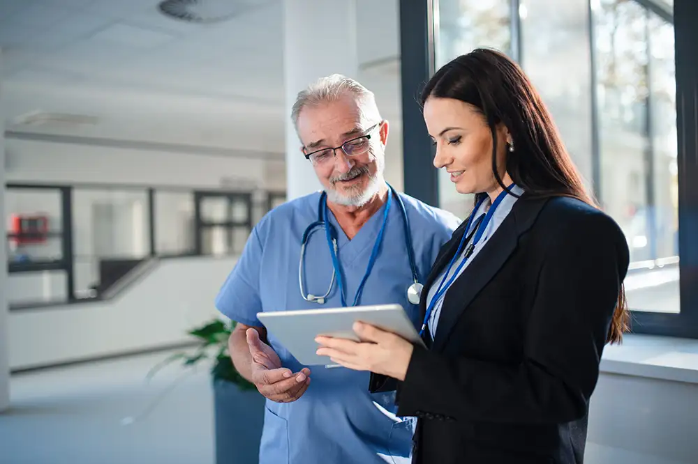 A businesswoman showing a physician something on a tablet while theyre standing in a medical office