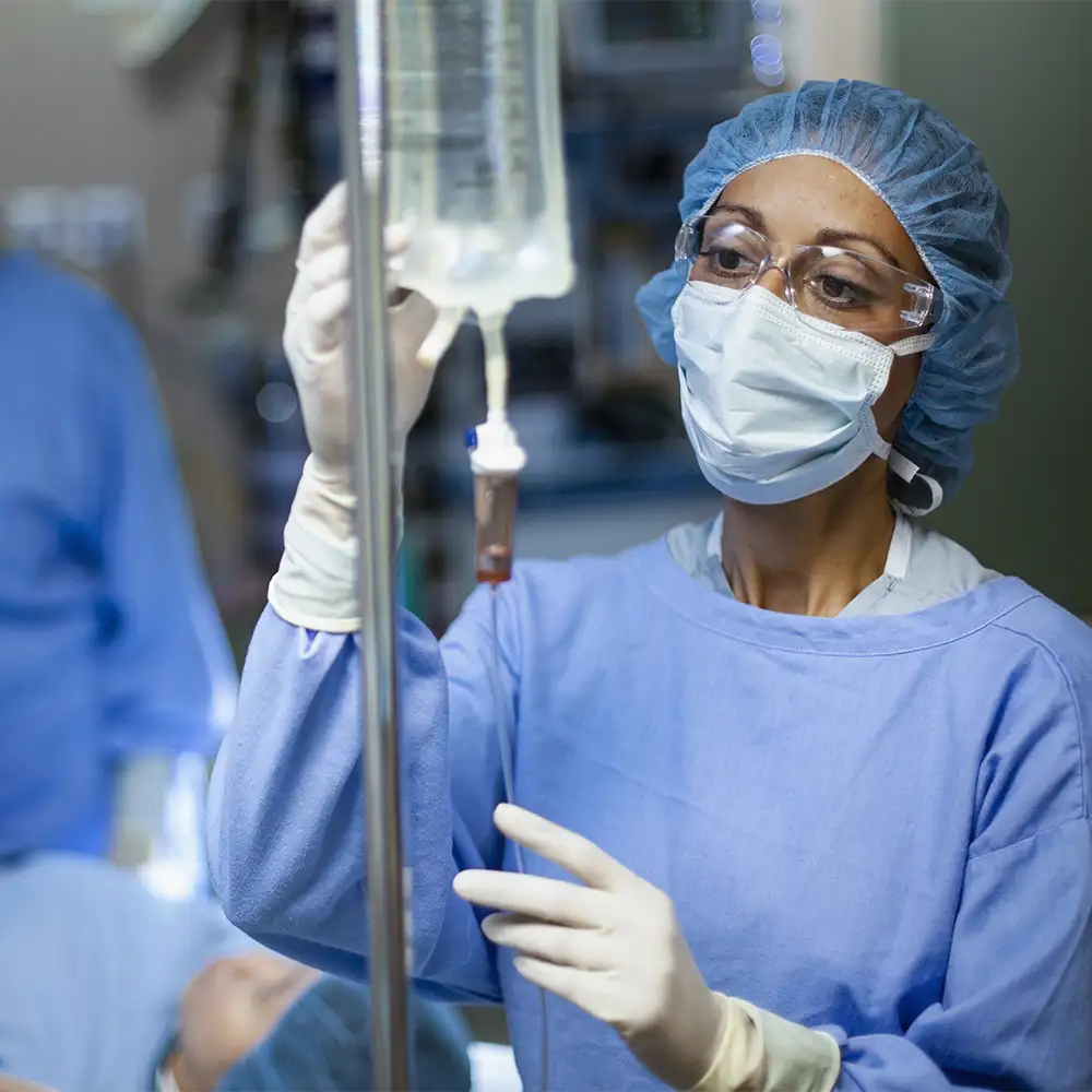 An anesthesiologist with a mask on monitoring the IV bag during a surgery
