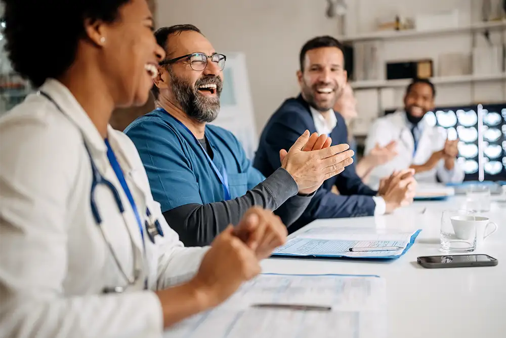 A table of doctors clapping and laughing